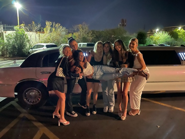 A group of people standing next to a white limo.