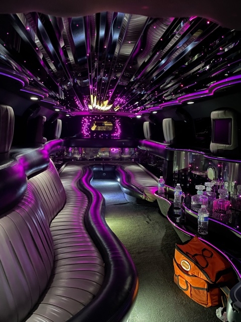 A purple and black party bus with lights on the ceiling.