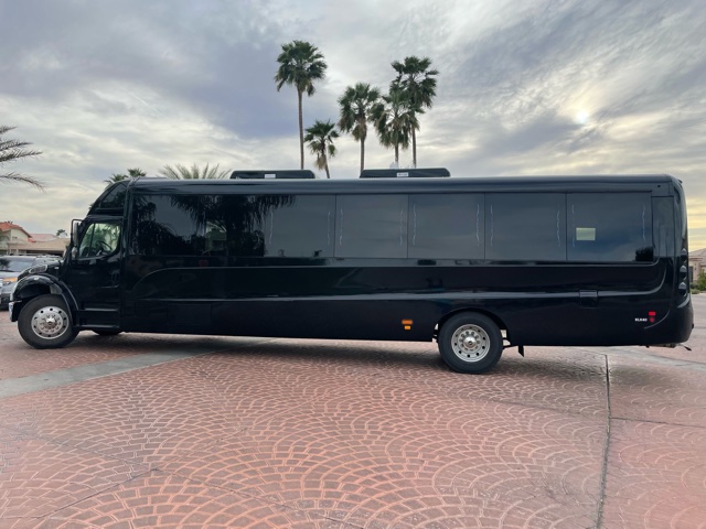 A black bus parked in the driveway of a building.